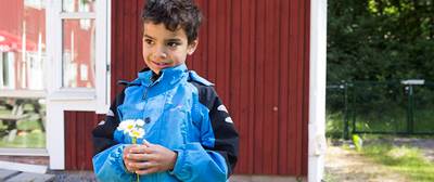 Pojke håller blommor i handen.